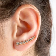 a woman's ear is adorned with gold and clear crystal studs, which are set on either side of the ear