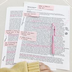 a person holding a pen over a piece of paper with sticky notes attached to it