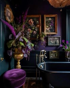 a bath tub sitting next to a purple chair in a room with paintings on the wall