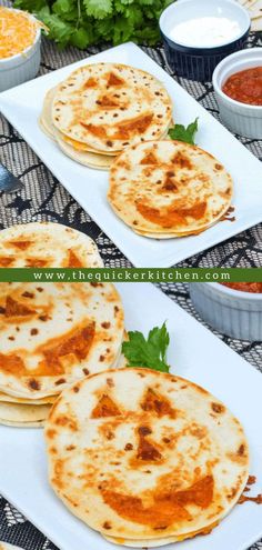 three quesadillas sitting on top of a white plate next to bowls of salsa