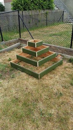 three raised wooden planters sitting in the middle of a yard