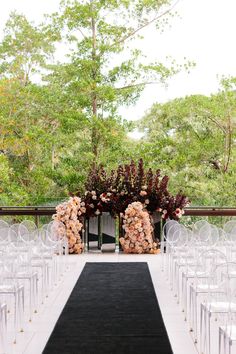 an outdoor ceremony setup with clear chairs and floral centerpieces on black runneres