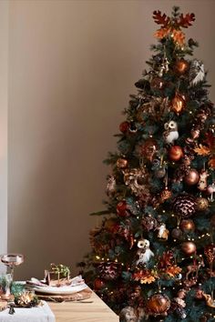 a christmas tree decorated with ornaments and other holiday decorations is shown in front of a dining room table