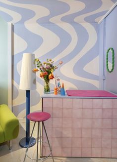 a bathroom with a pink counter and stools