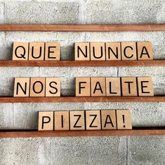 scrabble tiles spelling out the words que nunca nos faltie pizza