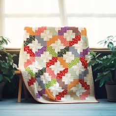 a quilted blanket sitting on top of a wooden chair next to a potted plant