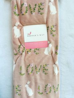 a pink blanket with white rabbits and green leaves on it, next to a tag that says pepper's way