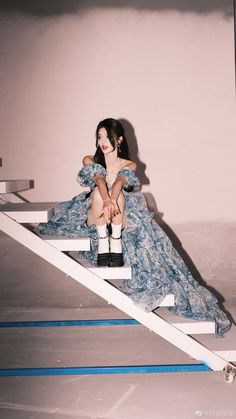 a woman sitting on top of a set of stairs in a blue dress and black boots