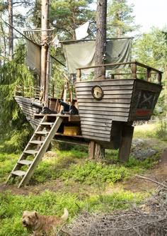 there is a boat that has been built in the woods with people on it and dogs nearby