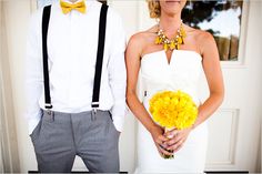 a man and woman standing next to each other in front of a door holding yellow flowers