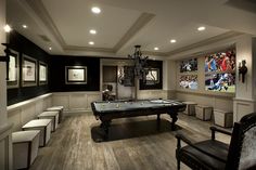 a game room with a pool table, chairs and pictures on the wall behind it