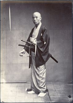 an old black and white photo of a man holding two samurai swords in his hands