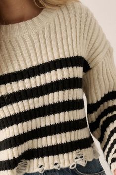 Striped, ribbed knit sweater. Distressed hem. Round neckline. Long sleeves. Drop shoulder. Natural waist length. Relaxed fit. 100% Cotton. Cozy Striped Ribbed Sweater, Striped Ribbed Crew Neck Sweater, Winter Striped Sweater With Ribbed Neckline, Striped Ribbed Sweater For Winter, Stretch Striped Ribbed Sweater, Striped Crew Neck Cropped Sweater For Winter, Stretch Knit Cropped Sweater With Ribbed Detail, Trendy Knit Sweater With Ribbed Neckline, Winter Striped Tops With Ribbed Neckline