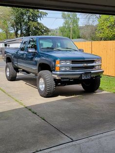 a blue truck parked in front of a wooden fence