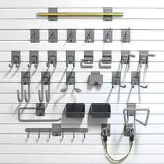 a bunch of metal objects hanging on a wall with hooks and clips attached to them