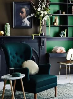 a green chair in front of a fireplace next to a vase with flowers on it