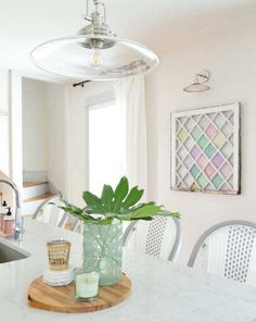 a kitchen with a marble counter top and white chairs in front of a window that has a potted plant on it