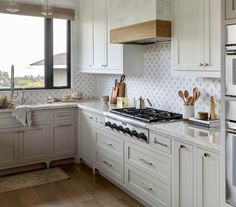 a kitchen with white cabinets and counter tops next to an open window overlooking the city