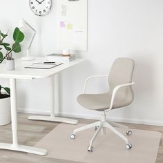 a white desk and chair in a room with a clock on the wall behind it