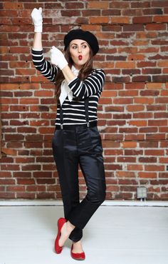 a woman in black and white striped shirt holding up her hand with red shoes on