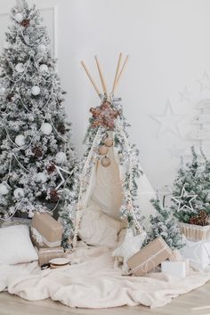 a teepee surrounded by christmas trees, presents and other holiday decorations in front of a white wall