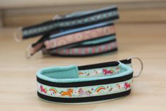 three different colored dog collars sitting on top of a wooden floor next to each other