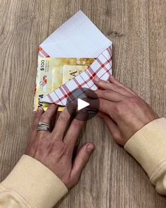 a person is making an origami airplane out of paper on a wooden table