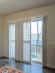 an empty living room with white shutters and wood floors