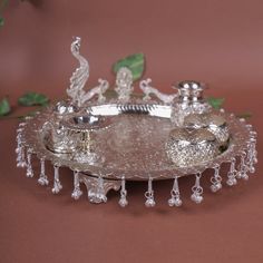 an ornate silver tray with beads and leaves on the edge, sitting on a red surface