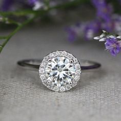 a close up of a diamond ring with flowers in the background