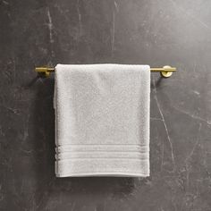 a white towel hanging on the wall next to a metal hook with two gold handles