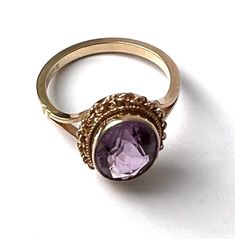 A beautiful solid 9ct gold amethyst dress ring, set with an oval cut amethyst weighing approximately 1.7 carats, bezel set within a rope twist frame with pierced shoulders. A delicate and sophisticated statement ring. The ring has British '375' 9K hallmarks, and the amethyst, light in colour, measures approximately 11 mm by 8 mm.  Stone: Natural amethyst Dimensions: Stone 11 mm x 8 mm Ring size: M Weight: 3 grams We have many other beautiful antique and vintage jewellery on our Etsy store, so pl Classic Amethyst Oval Cabochon Ring, Oval Amethyst Ring Stamped 14k, Formal Amethyst Oval Cabochon Ring, Formal Oval Cabochon Amethyst Ring, Hallmarked Oval Cabochon Amethyst Ring, Oval Cabochon Amethyst Ring For Formal Events, Oval Cabochon Amethyst Ring For Formal Occasions, Gold Oval Amethyst Cabochon Ring, Heirloom Style Purple Oval Amethyst Ring