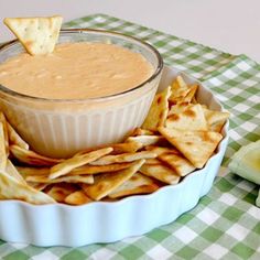 a bowl filled with dip and chips on top of a table