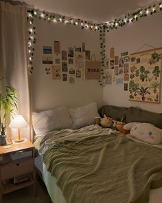 a bed with blankets and stuffed animals on it in a room decorated with string lights