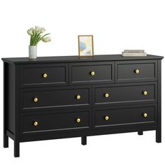 a black dresser with gold knobs and flowers on top, against a white background