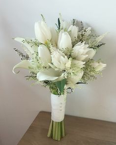 a bouquet of white flowers sitting on top of a wooden table