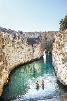 two people are wading through the water in an old stone bridge that has been built into it