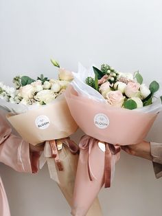 two women holding bouquets of flowers in their hands, one is pink and the other is white