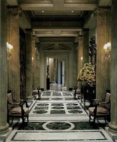 the hallway is lined with fancy chairs and vases filled with yellow flowers on either side