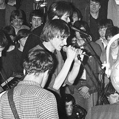 black and white photograph of people singing into microphones in front of a large crowd