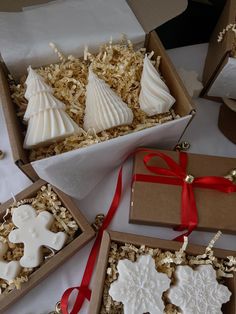 four decorated christmas cookies in boxes on a table with red ribbon and decorations around them