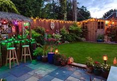 a backyard with lights and plants on the lawn, next to a small bar area