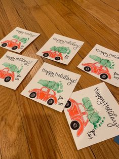 four cards with cars on them sitting on a wooden floor next to a pen and paper