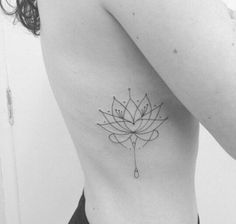 a black and white photo of a woman's stomach with a lotus tattoo on it