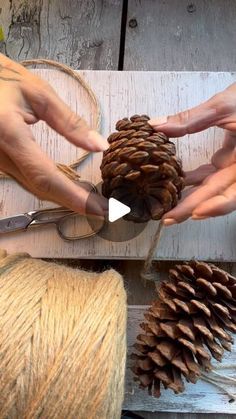 two hands are working on some pine cones