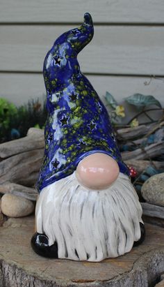 a blue and white gnome statue sitting on top of a tree stump