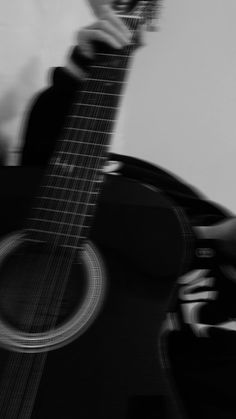 a person playing an acoustic guitar in black and white