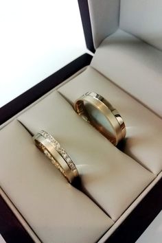 two gold wedding rings in a box with diamonds on the inside and outside of them