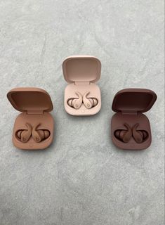 three earbuds are in an open case on the ground, one is empty