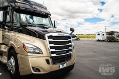 a truck parked in a parking lot with other trucks behind it and clouds in the sky